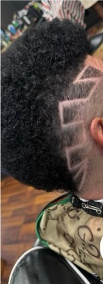 Back and side view of a tall curly top over a skin fade with a zigzag line carved through it