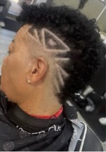 Side profile of a high skin fade with a zigzag design carved into it and curls left long on top