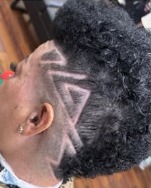 Side view of a fade with a triangular design carved above the ear and tight curls on top